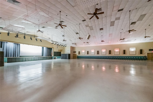 misc room with a towering ceiling, concrete floors, visible vents, and a ceiling fan