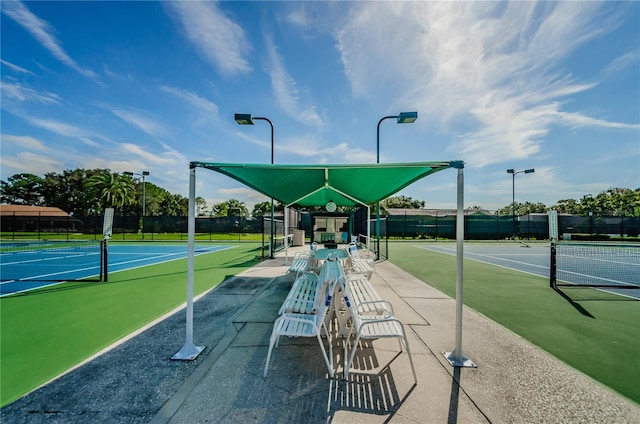 view of home's community featuring a tennis court and fence