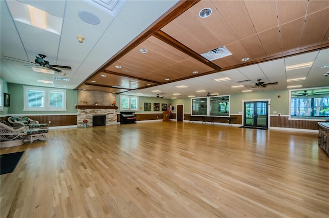 exercise room with light wood-style floors, a stone fireplace, a wainscoted wall, and visible vents