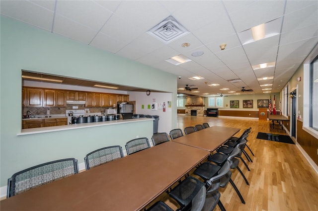 dining space with a paneled ceiling, visible vents, light wood-style floors, a ceiling fan, and baseboards