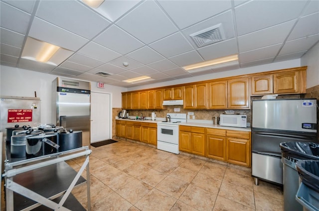 kitchen with light countertops, white appliances, visible vents, and under cabinet range hood