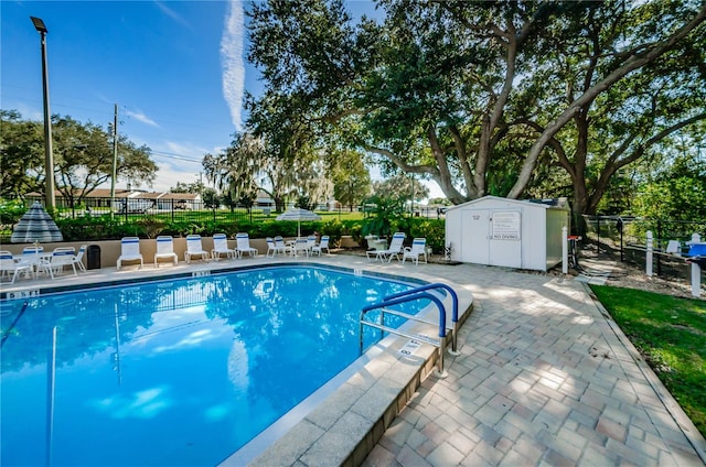 pool with an outdoor structure, fence, a storage shed, and a patio