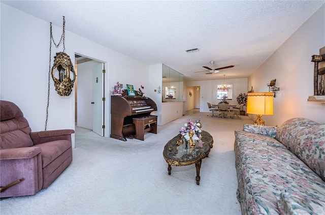 living area featuring carpet, visible vents, a textured ceiling, and ceiling fan with notable chandelier