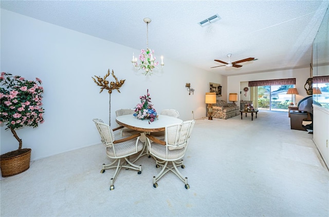 carpeted dining space with visible vents, a textured ceiling, and ceiling fan with notable chandelier