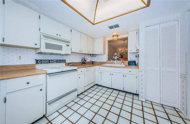 kitchen featuring white appliances, a sink, visible vents, white cabinets, and light countertops