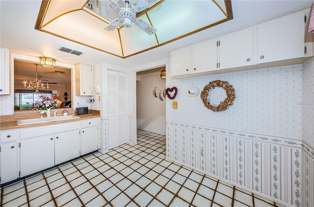 kitchen with white cabinets, visible vents, a sink, and decorative light fixtures