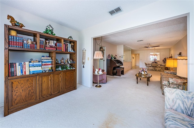 sitting room featuring a textured ceiling, ceiling fan, visible vents, and light colored carpet