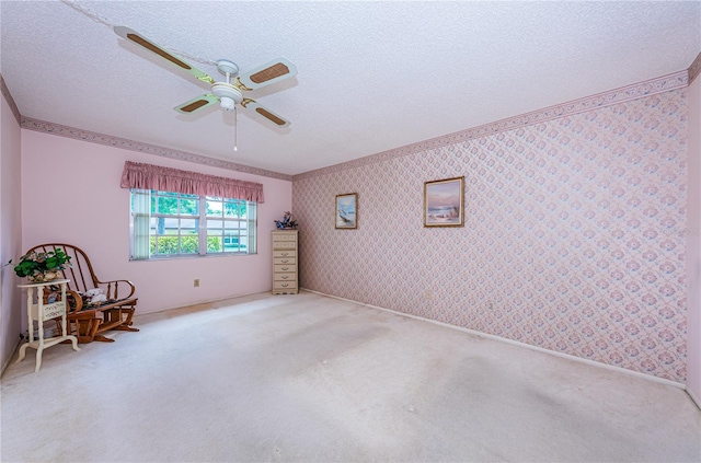 unfurnished room with a textured ceiling, carpet flooring, a ceiling fan, and wallpapered walls