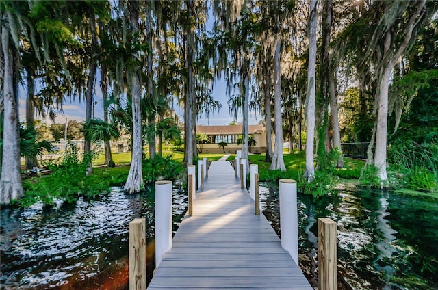 dock area featuring a lawn, a water view, and fence