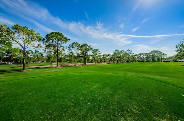 view of community featuring view of golf course and a yard