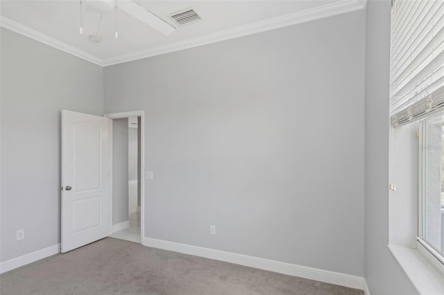 spare room featuring a wealth of natural light, crown molding, and light colored carpet