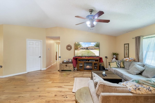 living room featuring ceiling fan, a fireplace, lofted ceiling, and wood-type flooring