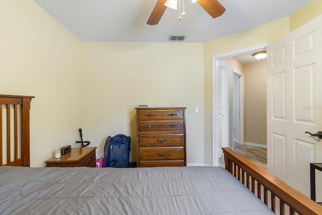 bedroom with hardwood / wood-style floors, ceiling fan, and a textured ceiling