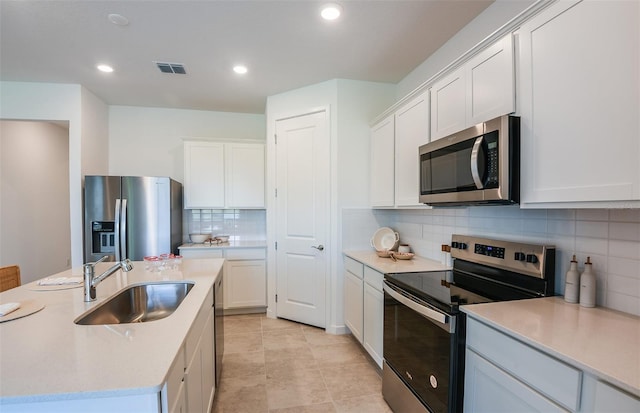 kitchen with appliances with stainless steel finishes, white cabinets, sink, and tasteful backsplash