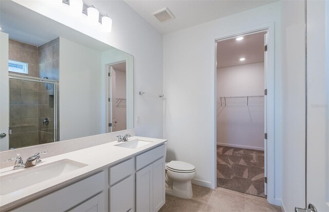 bathroom featuring tile patterned flooring, double vanity, an enclosed shower, and toilet