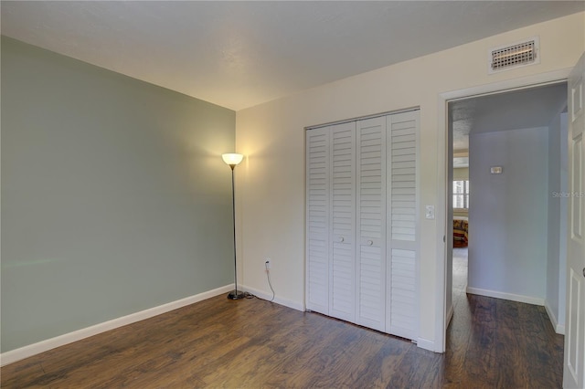 unfurnished bedroom with dark hardwood / wood-style floors and a closet