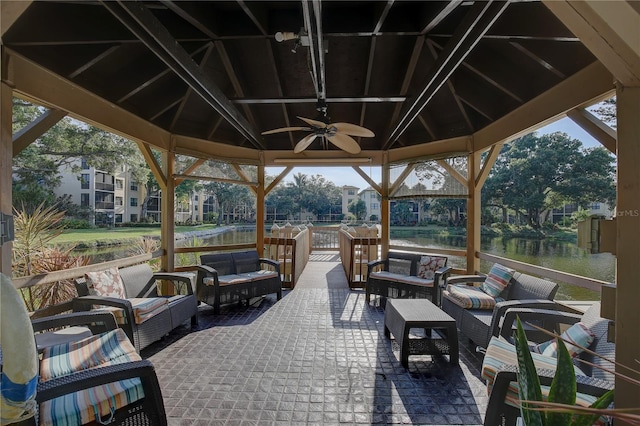 view of patio / terrace featuring a water view, ceiling fan, an outdoor living space, and a gazebo