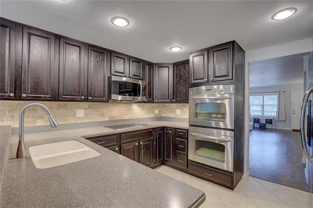 kitchen with dark brown cabinetry, sink, tasteful backsplash, and stainless steel appliances