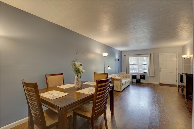 dining area with dark wood-type flooring and a textured ceiling