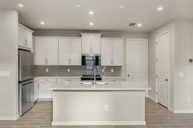 kitchen featuring white cabinetry, a center island with sink, sink, and appliances with stainless steel finishes