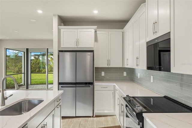 kitchen with light stone countertops, sink, white cabinets, and stainless steel appliances