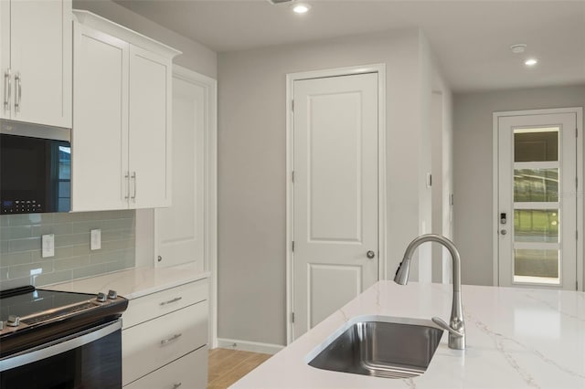 kitchen with light stone countertops, sink, decorative backsplash, white cabinets, and appliances with stainless steel finishes