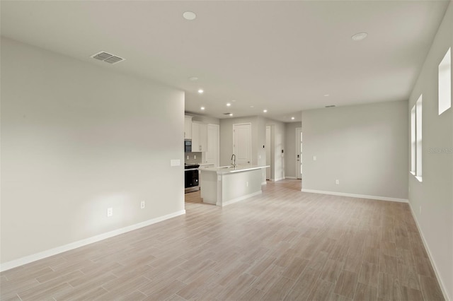 unfurnished living room featuring sink and light wood-type flooring