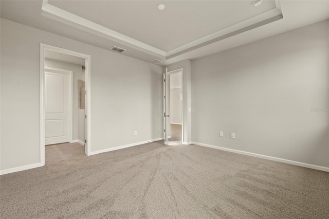 carpeted empty room with a raised ceiling