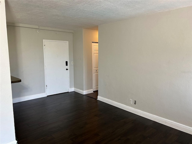 empty room featuring a textured ceiling and dark hardwood / wood-style floors