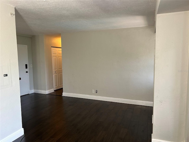 empty room with dark hardwood / wood-style floors and a textured ceiling