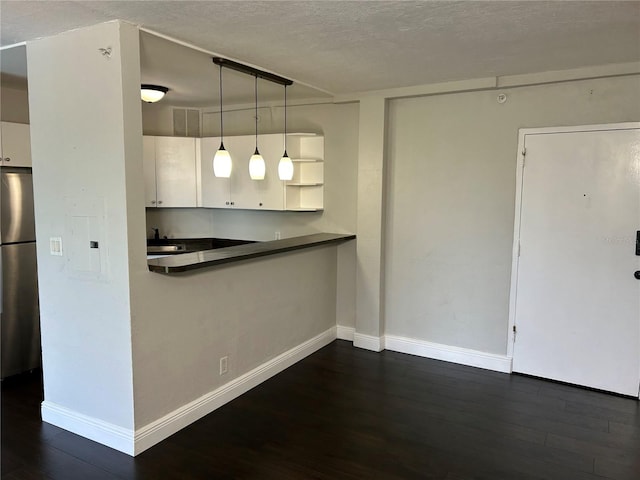 kitchen featuring hanging light fixtures, a textured ceiling, dark hardwood / wood-style flooring, white cabinetry, and stainless steel refrigerator