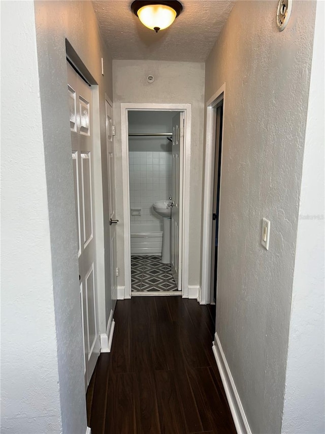 hall with dark hardwood / wood-style floors and a textured ceiling