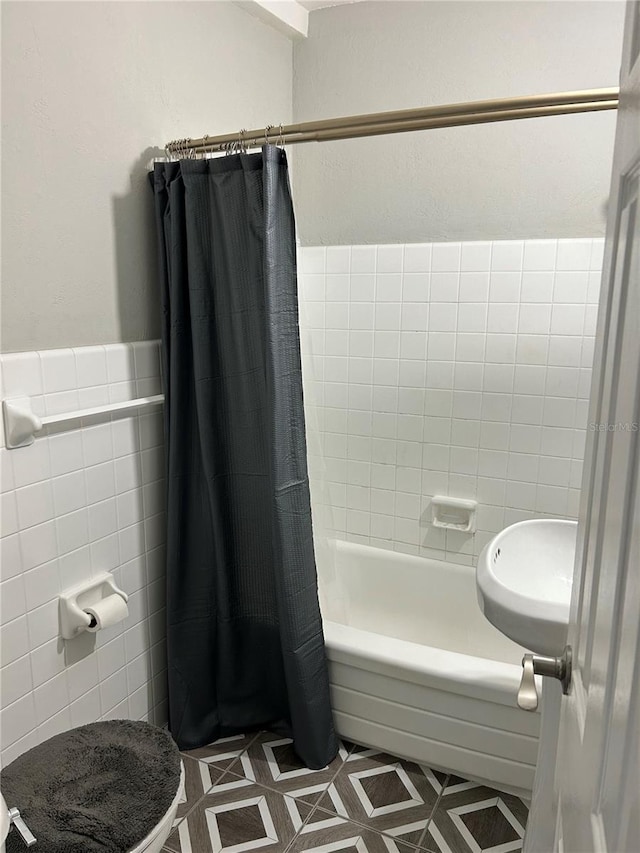 full bathroom with tile patterned floors, sink, toilet, shower / bath combo with shower curtain, and tile walls