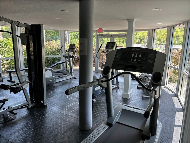 gym featuring floor to ceiling windows, a textured ceiling, and a wealth of natural light