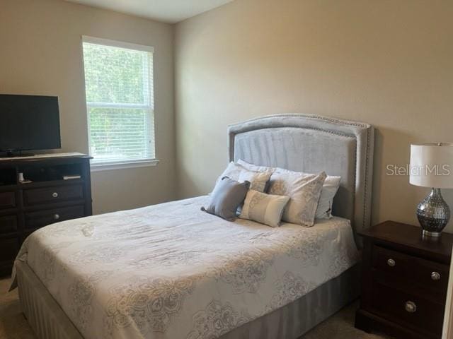 bedroom with dark colored carpet and multiple windows