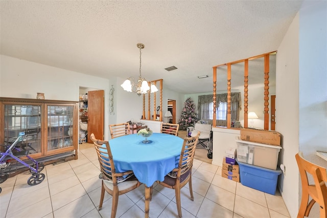 dining area featuring a textured ceiling, a notable chandelier, and light tile patterned floors