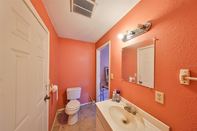 bathroom featuring tile patterned flooring, toilet, a textured ceiling, and vanity