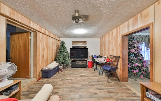 sitting room featuring wooden walls, a textured ceiling, and light hardwood / wood-style flooring