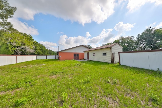 exterior space with fence, metal roof, and a lawn