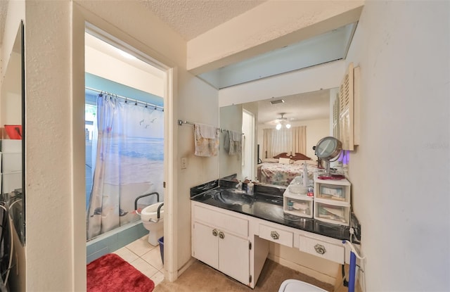 ensuite bathroom featuring curtained shower, toilet, ensuite bathroom, vanity, and a textured ceiling