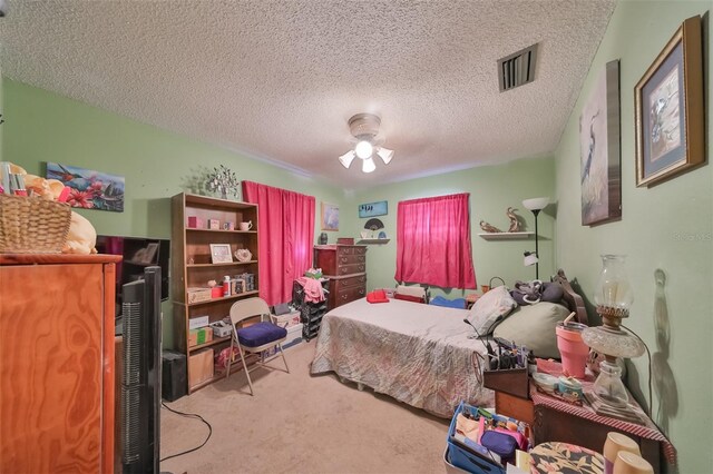 bedroom featuring light carpet, a ceiling fan, visible vents, and a textured ceiling