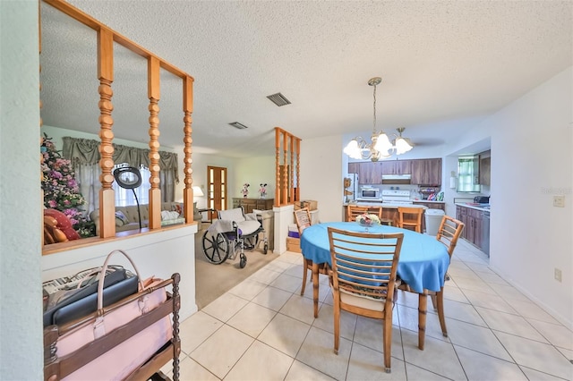 dining area featuring a textured ceiling, light tile patterned floors, visible vents, and a notable chandelier