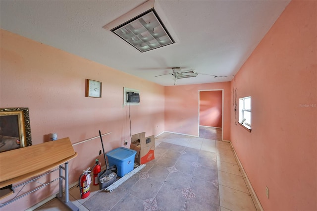 unfurnished room featuring tile patterned flooring, a wall mounted air conditioner, ceiling fan, and baseboards