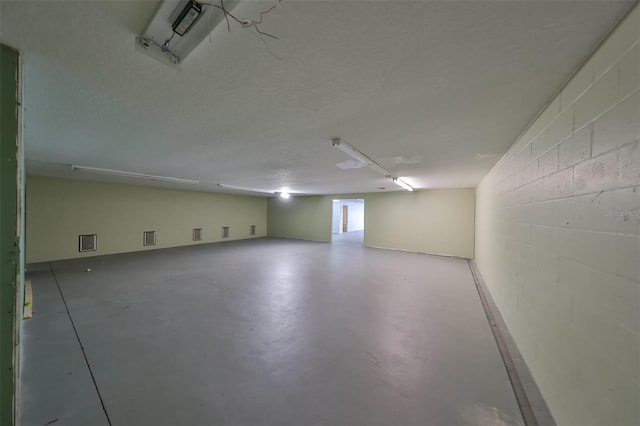 unfurnished room featuring concrete block wall, concrete floors, and a textured ceiling