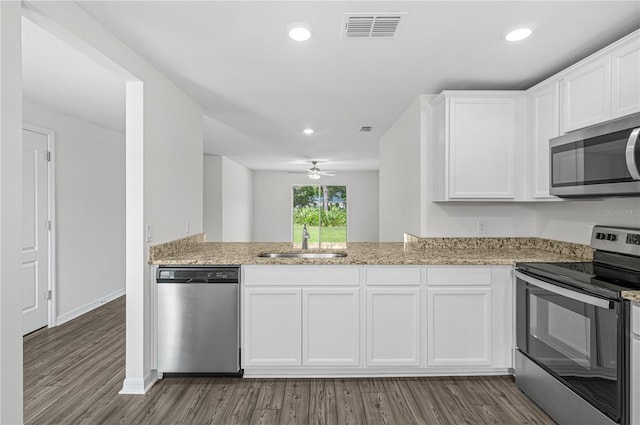 kitchen featuring dark wood-type flooring, stainless steel appliances, sink, light stone countertops, and white cabinets