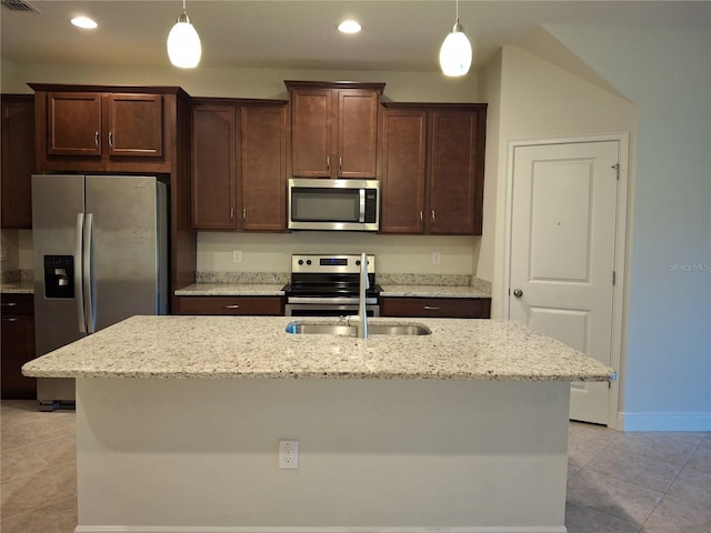 kitchen featuring appliances with stainless steel finishes, light stone countertops, decorative light fixtures, and sink