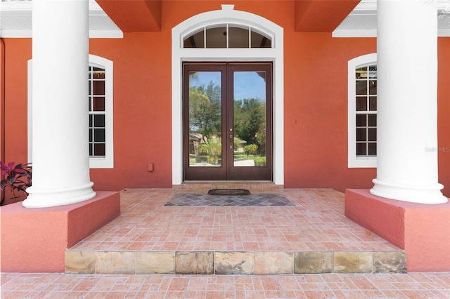 view of exterior entry featuring french doors and stucco siding