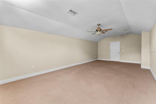 empty room with ceiling fan, a textured ceiling, carpet, and vaulted ceiling