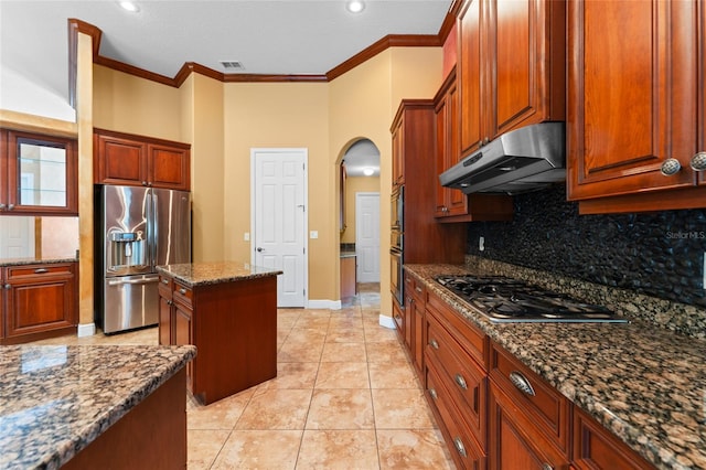 kitchen with dark stone countertops, stainless steel appliances, light tile patterned floors, backsplash, and a center island