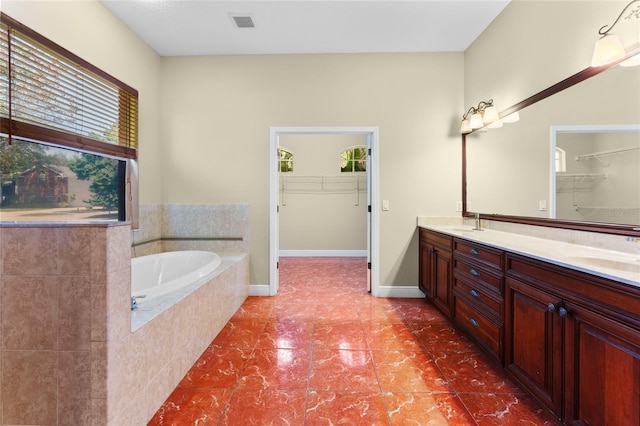 bathroom featuring double sink vanity, tiled bath, and tile patterned flooring